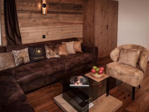 ein Wohnzimmer mit einem braunen Sofa und einem Stuhl in der Unterkunft Apartment Kirchplatz by Interhome in Zermatt