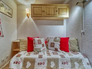 レ・メニュアールにあるApartment Gentianes by Interhomeのベッドルーム1室(赤と白の枕が備わるベッド1台付)