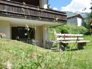 a wooden bench sitting in the grass next to a building at Apartment Am Sonnenhang by Interhome in Churwalden