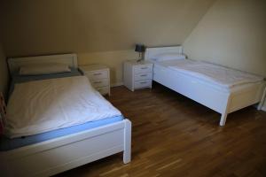 two beds in a small room with wooden floors at Ademi in Süderhöft