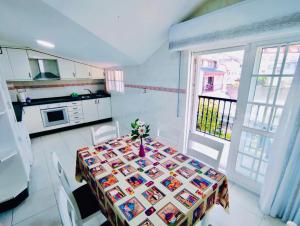a dining room with a table and a kitchen at CASA GLORIA - ÁTICO BALCÓN in Combarro