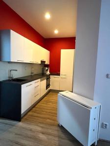 a kitchen with white cabinets and a red wall at Bohemian Apartments near the Center in Prague