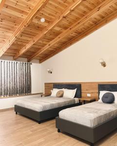 two beds in a room with wooden ceilings at Mili Hotel in Berat