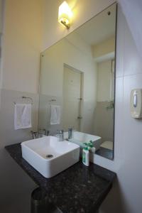 a bathroom with a white sink and a large mirror at Ixora Suites in Bangalore