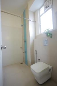 a bathroom with a toilet and a shower with a window at Ixora Suites in Bangalore