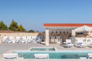 a patio with a pool and chairs and a bar at Anna Mare Luxury Apartments in Afitos