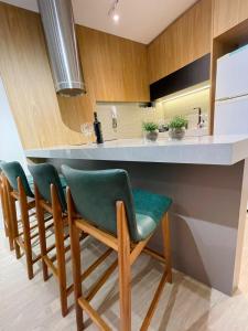 a kitchen with a bar with green chairs at Conforto e a melhor localização in Balneário Camboriú