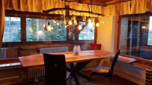 comedor con mesa de madera y ventanas en Ferienhäuser zum Badeweiher, en Neuschönau