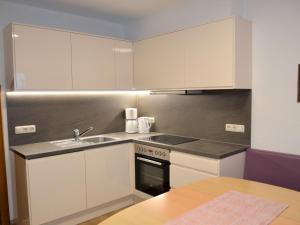 een keuken met witte kasten, een wastafel en een fornuis bij Apartment Hedwig Jäger by Interhome in Kappl +25 foto's