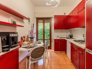 una cocina con armarios rojos y una mesa con sillas. en Villa Vittoria by Interhome, en Bellagio