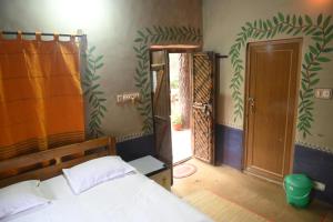 a bedroom with a bed and an open door at Ram Shyam Village Resort in Shānti Niketan