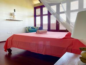 a room with a bed with a red blanket at Gîtes KUMQUAT in Petit-Bourg