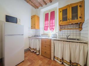 La cuisine est équipée d'un réfrigérateur blanc et de placards en bois. dans l'établissement Apartment Le Fornaci-1 by Interhome, à San Quirico di Moriano