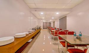 a long dining room with red chairs and white plates on tables at Treebo Trend Golden Swan Airport Free Pick & Drop in Chennai