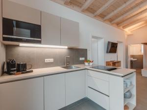 cocina con armarios blancos y microondas en Apartment Das Georgen- Großglockner by Interhome en Fürstau