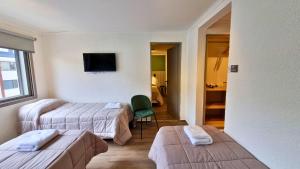 um quarto de hotel com duas camas e uma cadeira verde em M382 Hotel Bariloche em San Carlos de Bariloche