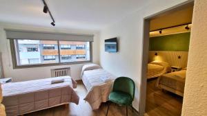 Cette chambre comprend deux lits et une chaise verte. dans l'établissement M382 Hotel Bariloche, à San Carlos de Bariloche