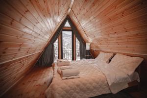 a bed in a wooden room with a large window at M&L in Mestia