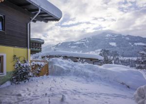 a house covered in snow with a mountain in the background at Latina, Brixental Tirol - auch im Sommer wunderschön! in Westendorf