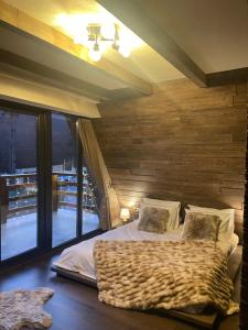 a bedroom with a bed with a wooden wall at Valea Mosului - Cozy A Frame in Petroşani