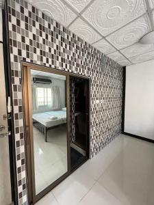 Habitación con espejo y pared de azulejos. en LSN Mansion, en Ban Na Song