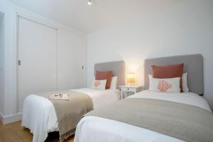1 dormitorio con 2 camas y almohadas blancas y rojas en Genteel Home San Agustín, en Málaga