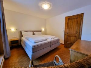 een slaapkamer met een bed en een houten deur bij Apartment Rätia III by Interhome in Pfunds