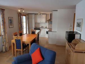 eine Küche und ein Wohnzimmer mit einem Tisch und einem blauen Sofa in der Unterkunft Apartment Tga Stgirat Erdgeschoss by Interhome in Malmigiuer