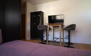 a bedroom with a bed and two chairs and a television at Garconniere in Niedernsill in Niedernsill