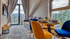 a dining room with a table and a couch at Apartamenty z basenem ROYAL APARTS Złoty Horyzont VIP, SPA i restauracja in Szklarska Poręba