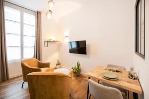 een woonkamer met een tafel en stoelen en een televisie bij Le Laurencin Sens - Le Keys in Sens
