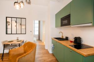 une cuisine avec des placards verts et une table avec une chaise dans l'établissement Le Laurencin Sens - Le Keys, à Sens
