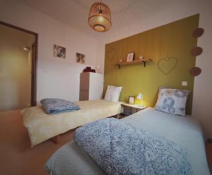 een slaapkamer met 2 bedden en een groene muur bij Le Canal Wi-Fi Parking Jardin Piscine 15 mn de Béziers in Colombiers