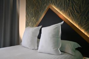 ein Bett mit weißen Kissen und einem hölzernen Kopfteil in der Unterkunft LOGIS Hôtel Borel in Dunkerque