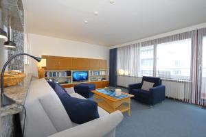 a living room with a white couch and blue chairs at Haus Metropol 175 OB in Westerland (Sylt)