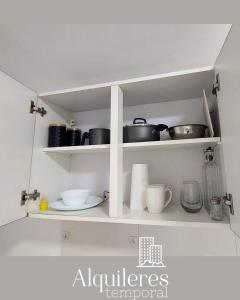 a kitchen with white shelves with pots and pans at suipacha 437 in Rosario