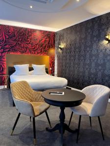 - une chambre avec un lit, une table et des chaises dans l'établissement LOGIS Hôtel Borel, à Dunkerque