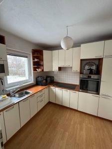 a kitchen with white cabinets and a sink and a window at Villa Osik in Sarajevo