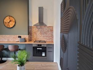 a kitchen with a stove and a clock on the wall at Stay @ The Old Bank Apartments, Burton on Trent in Burton upon Trent