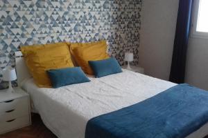 1 dormitorio con 1 cama con almohadas azules y amarillas en Le Tilleul en périogord Noir proche Sarlat, en Paulin