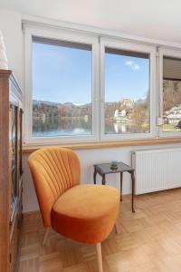 una silla naranja en una habitación con 2 ventanas en Lakeview Bled Heaven Apartments, en Bled