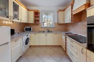 cocina con armarios blancos, lavadora y secadora en Lakeview Bled Heaven Apartments, en Bled