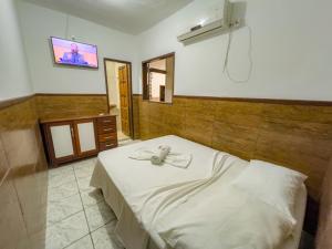 1 dormitorio con 1 cama y TV en la pared en pousada Vitoria, en Morro de São Paulo