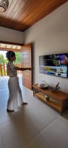 a woman is opening a window in a living room at Casa noites tropicais in Imbassai