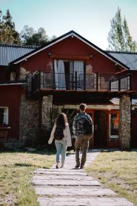 a man and woman walking in front of a building at Equs Posada de Campo in San Carlos de Bariloche
