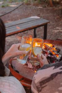 two people holding up glasses of water next to a fire at Equs Posada de Campo in San Carlos de Bariloche