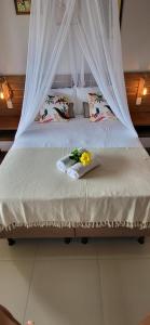 a bed with a white canopy with flowers on it at Casa noites tropicais in Imbassai