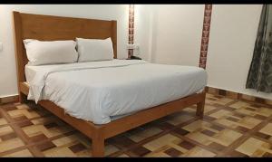 een bed met witte lakens en kussens in een slaapkamer bij FabHotel Rudraksh Resort in Mussoorie