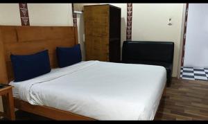 a bedroom with a large white bed with blue pillows at FabHotel Rudraksh Resort in Mussoorie