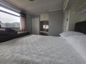 a bedroom with a large white bed with a window at Almost Heaven in Acton Trussell
